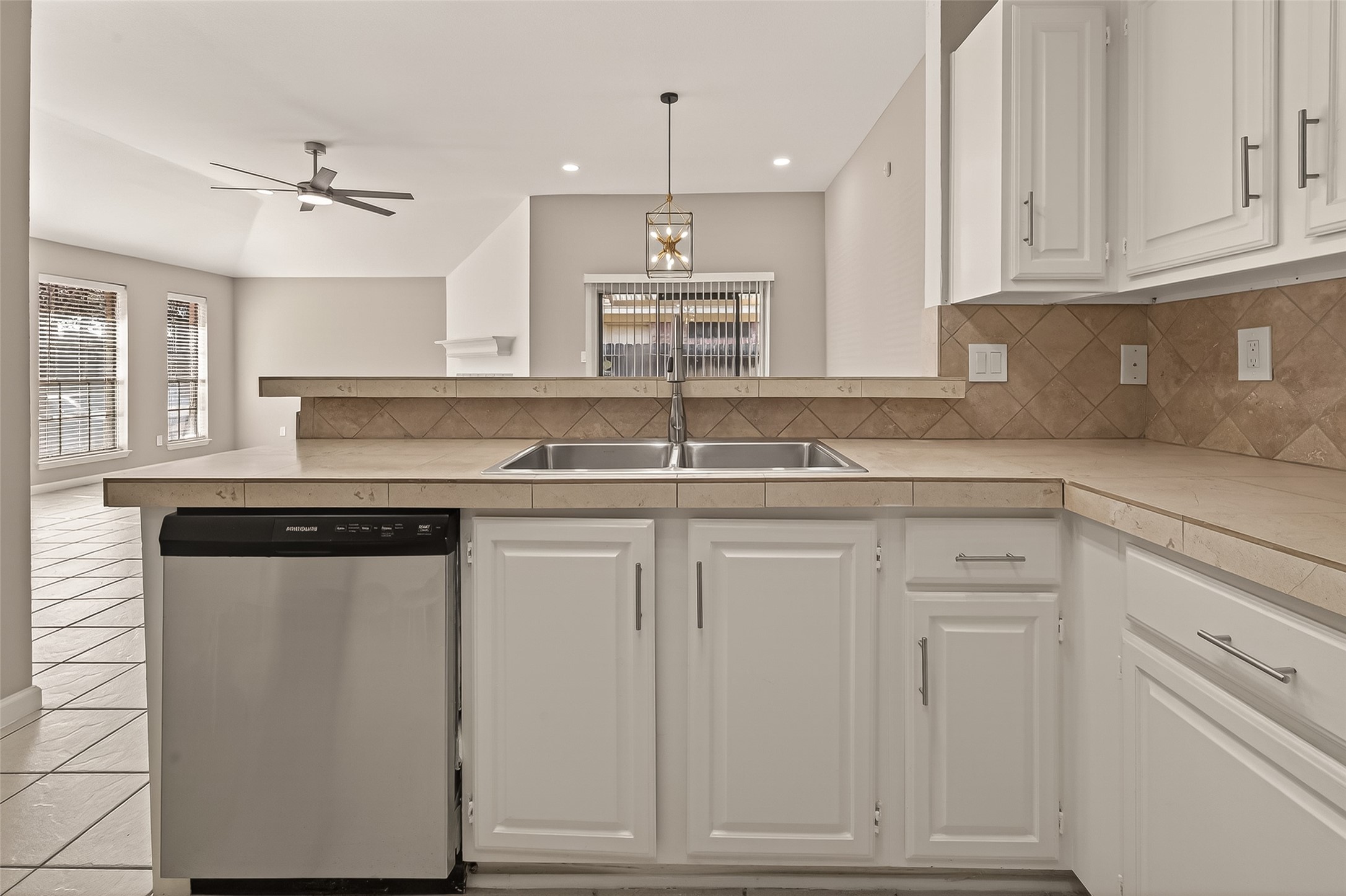 10810 Umber Court Houston, TX 77099 - Photo 11 of 43 A close-up detail of the kitchen workspace, highlighting the neutral tile backsplash and the ample counter space provided by the breakfast bar.