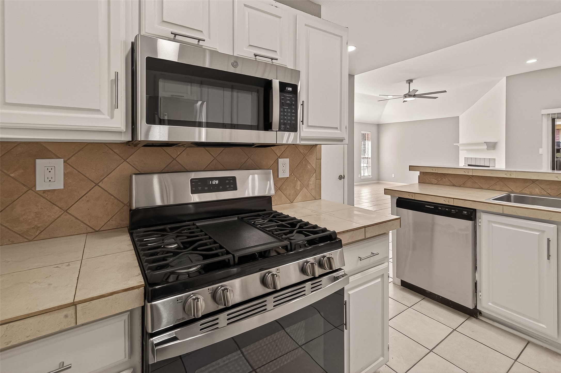 10810 Umber Court Houston, TX 77099 - Photo 15 of 43 A look at the stainless steel appliance suite, highlighting the updated gas stove and matching microwave set against the clean white cabinetry.