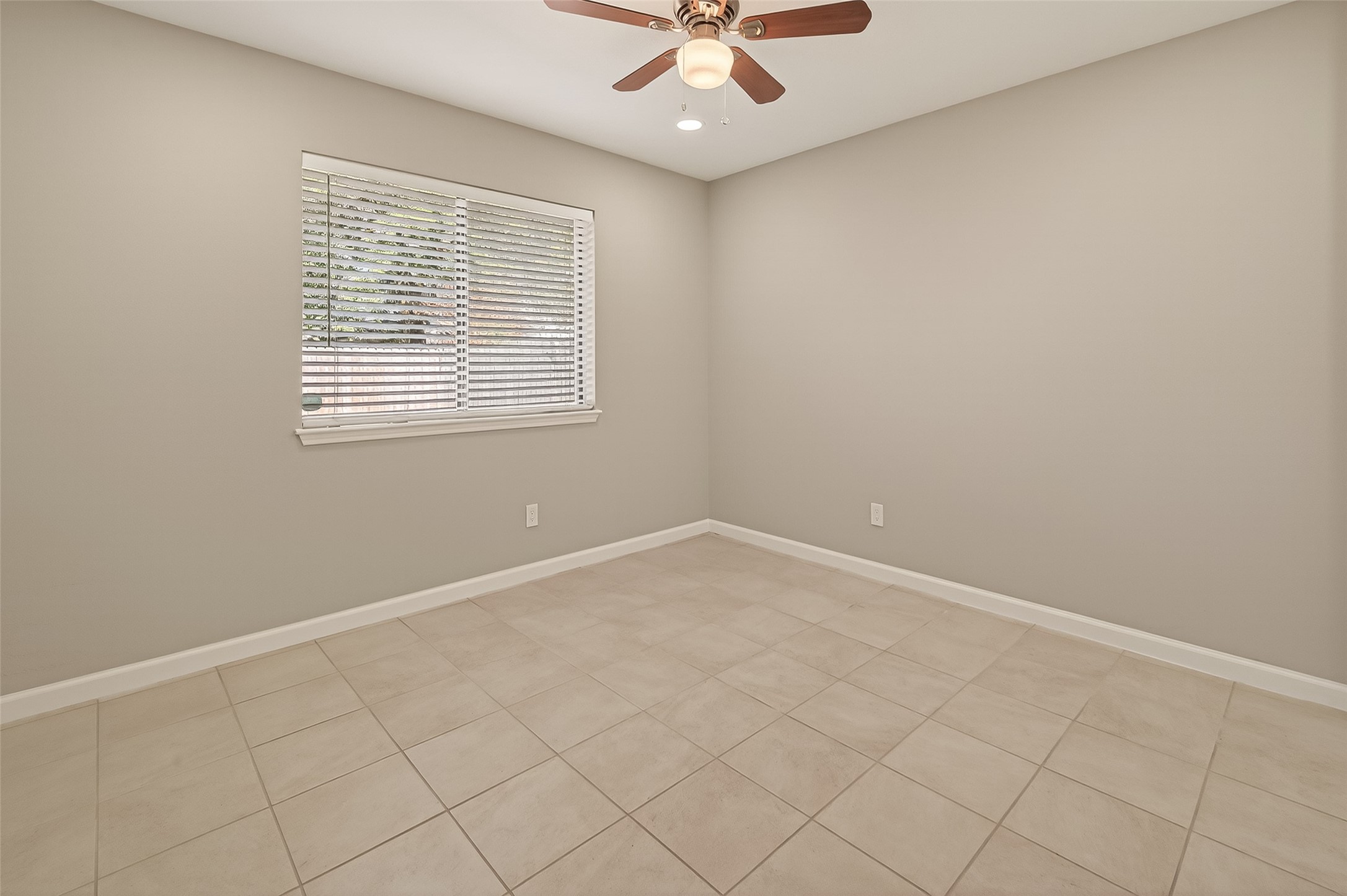 10810 Umber Court Houston, TX 77099 - Photo 19 of 43 This bright and versatile secondary bedroom features a large window that fills the space with natural light. The modern ceiling fan and neutral tile flooring ensure a comfortable, easy-to-maintain environment for guests or a home office.