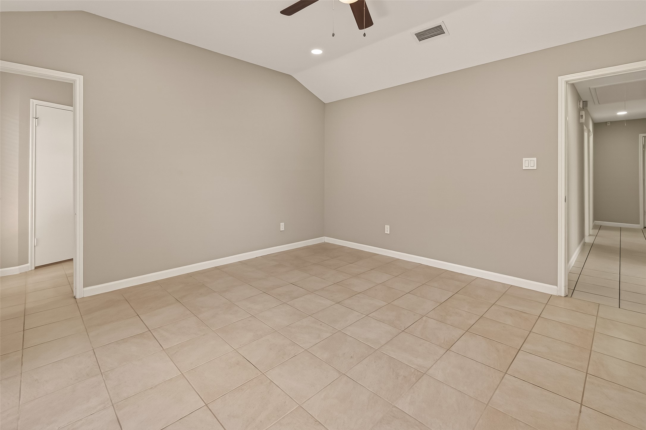 10810 Umber Court Houston, TX 77099 - Photo 27 of 43 This room features neutral-colored walls and tile flooring, with a ceiling fan providing light and ventilation. It has a simple, clean design with two doorways leading to adjacent areas, creating a spacious and versatile living space.