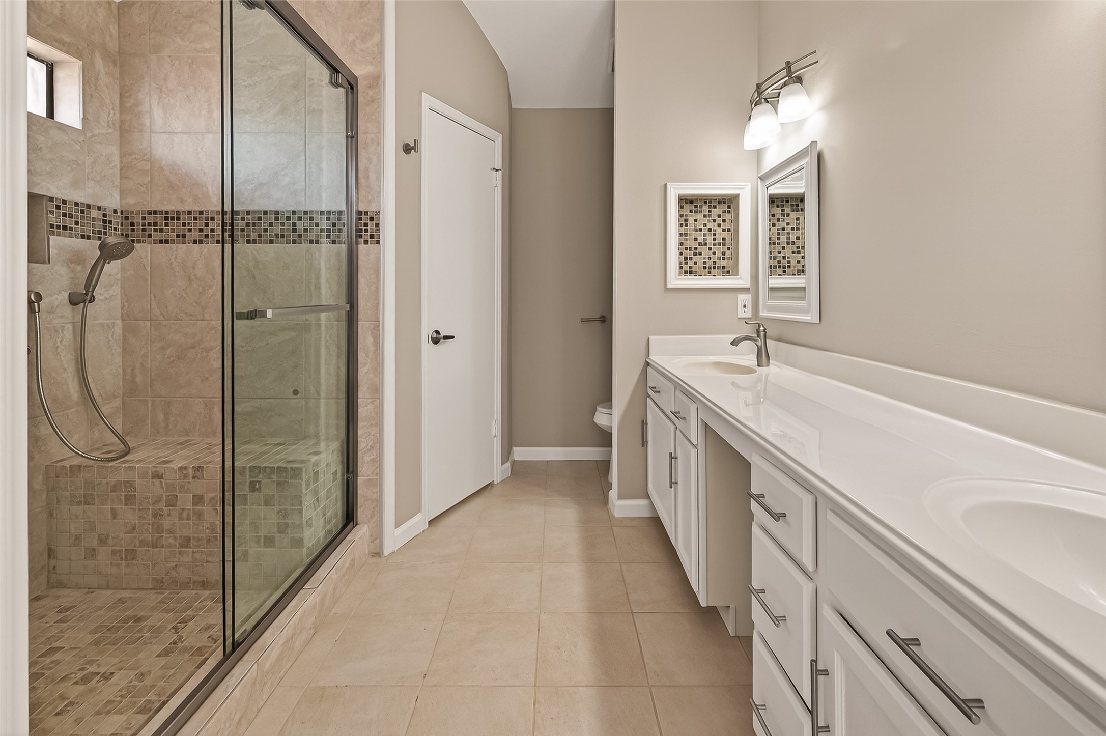 10810 Umber Court Houston, TX 77099 - Photo 29 of 43 This modern bathroom features a spacious glass-enclosed shower with decorative tile accents, a double vanity with ample storage, and elegant lighting, offering a clean and contemporary feel.