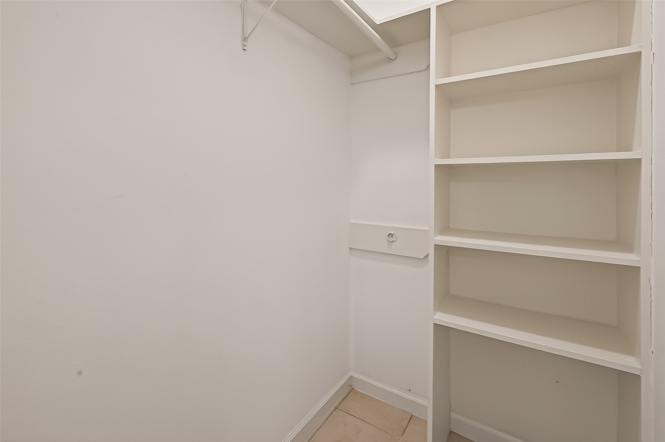 10810 Umber Court Houston, TX 77099 - Photo 34 of 43 This is a compact, white walk-in closet featuring built-in shelves and a hanging rod, offering efficient storage space.