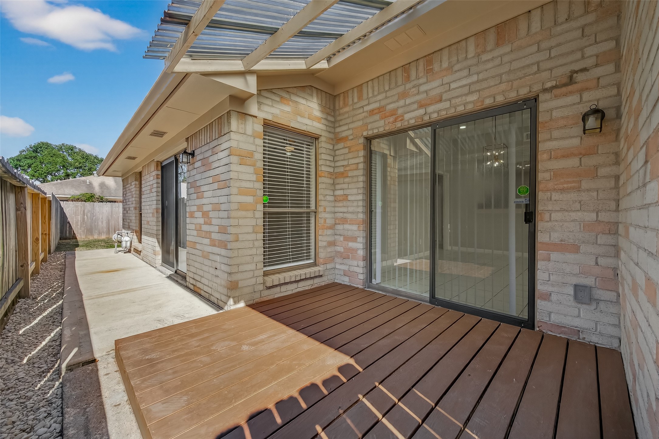 10810 Umber Court Houston, TX 77099 - Photo 38 of 43 This perspective showcases the deck's seamless connection to the home via the sliding glass doors, creating an effortless indoor-outdoor flow. The elevated platform provides a clean, dry area for outdoor furniture and overlooks the rest of the backyard space.