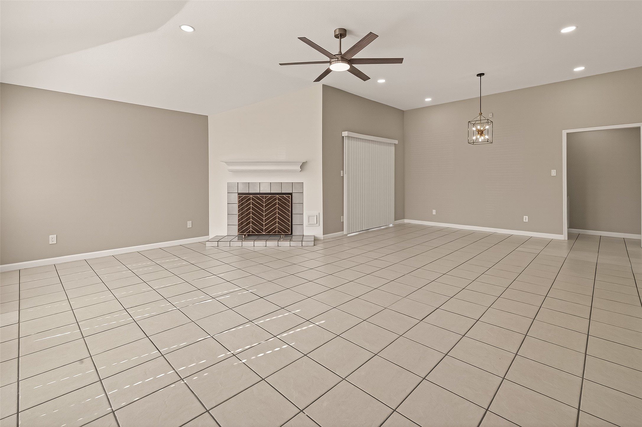 10810 Umber Court Houston, TX 77099 - Photo 4 of 43 A view of the living area showcasing the seamless flow between the living and dining spaces. The neutral tile flooring, recessed lighting, and the modern, six-blade ceiling fan that anchors the room.