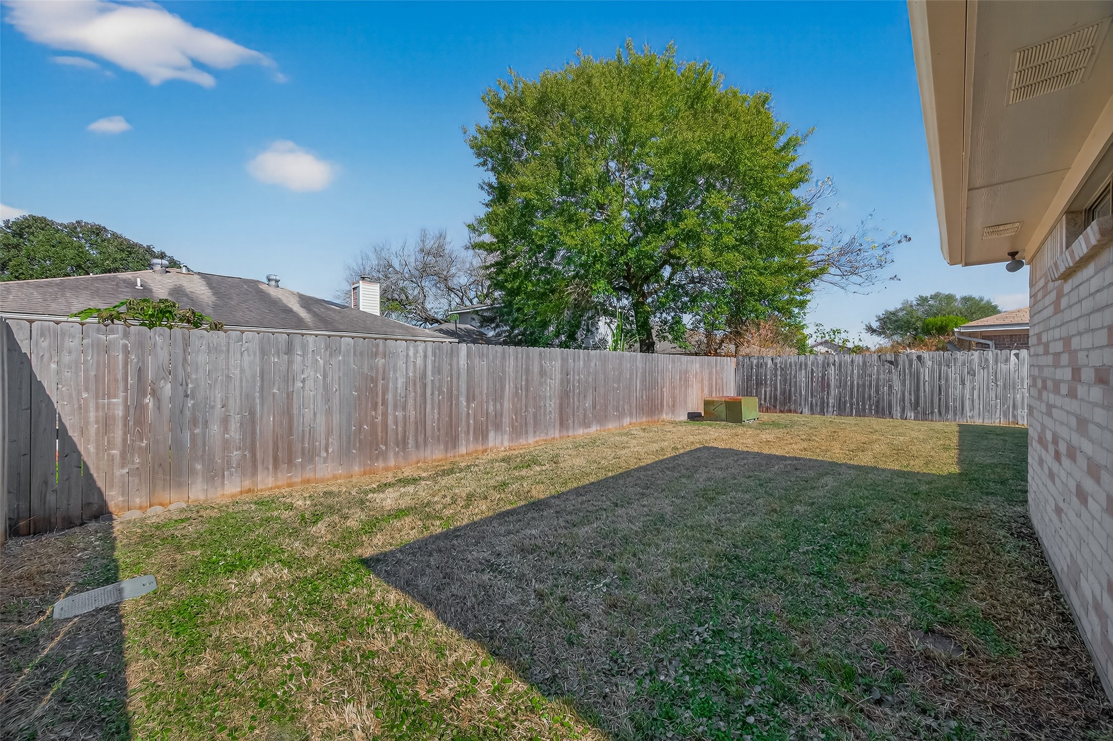 10810 Umber Court Houston, TX 77099 - Photo 43 of 43 This photo showcases a spacious backyard with a wooden privacy fence, mature tree, and grassy area, perfect for outdoor activities and relaxation.