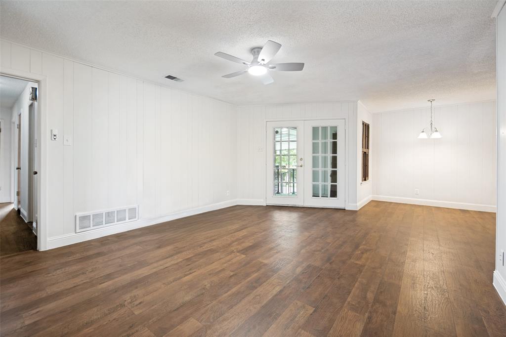 Spacious room featuring wood-finish flooring, white panel walls, and French doors