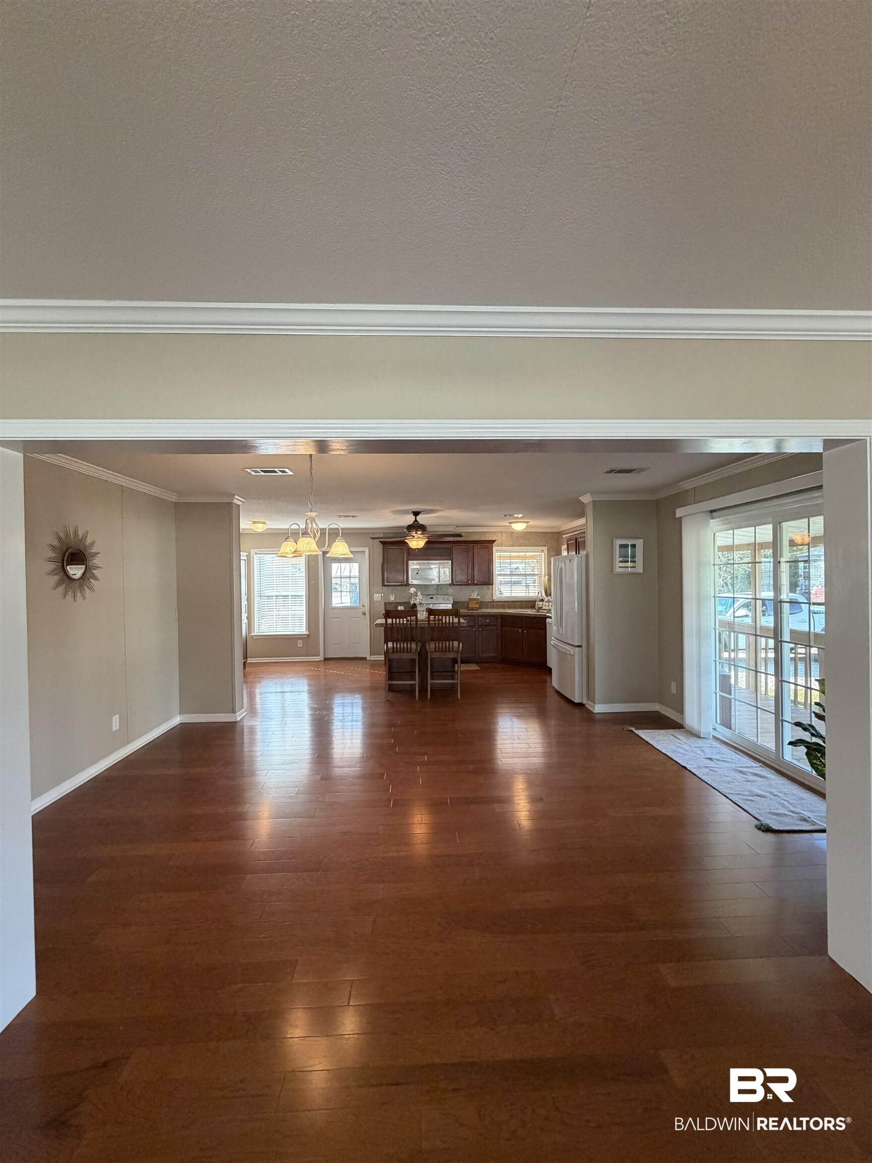 675 Escambia Loop Lillian, AL 36549 - Photo 13 of 44 Unfurnished living room featuring dark wood-style floors, crown molding, ceiling fan, and a chandelier