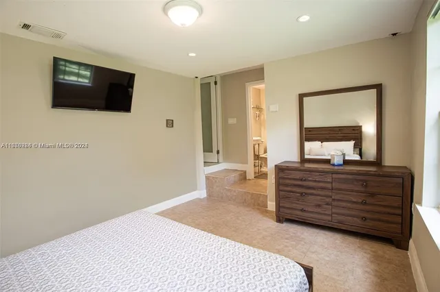 a spacious bedroom with a bed and a flat screen television