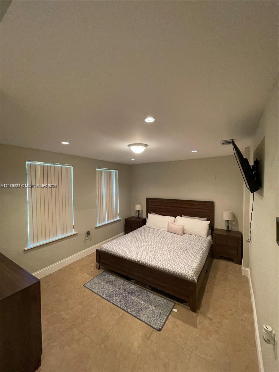 1531 Moffett Street Hollywood, FL 33020 - Photo 17 of 34 a spacious bedroom with a bed and a flat screen television