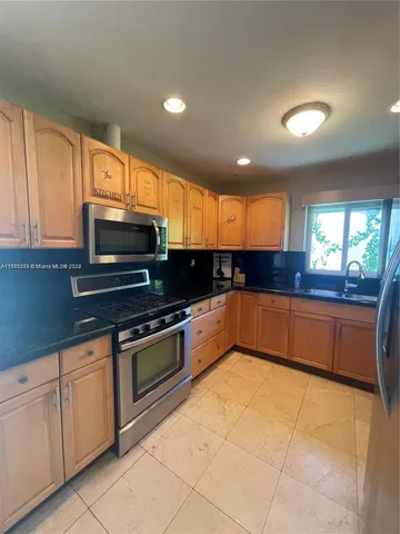 a large kitchen with stainless steel appliances granite countertop a stove a sink and a microwave