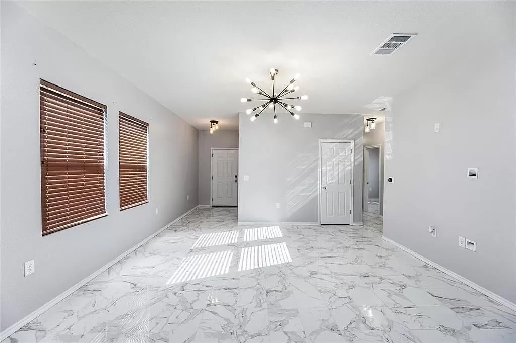 13021 Foreston Drive Austin, TX 78754 - Photo 4 of 17 Empty room with a chandelier and light marble finish flooring