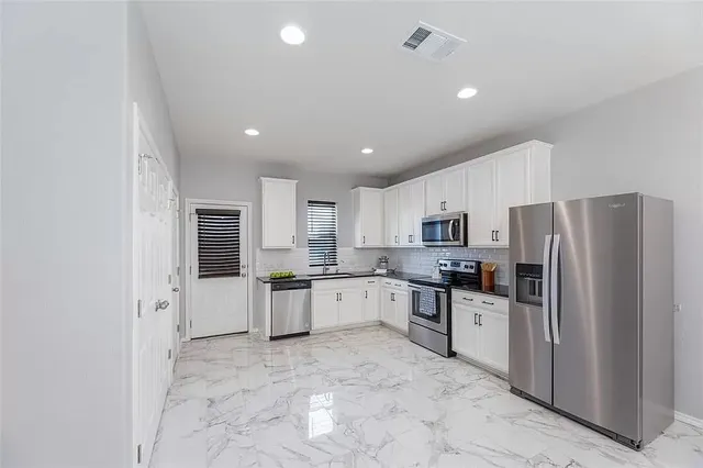 a view of a livingroom with a chandelier fan and windows