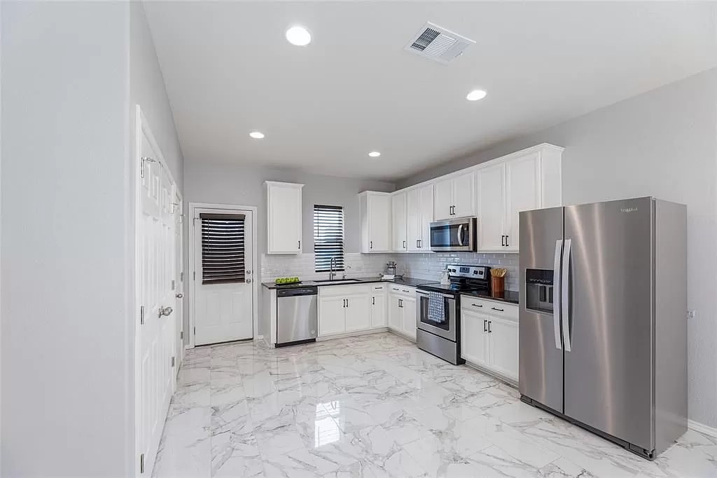 13021 Foreston Drive Austin, TX 78754 - Photo 5 of 17 Kitchen with stainless steel appliances, light marble finish flooring, white cabinets, decorative backsplash, and recessed lighting