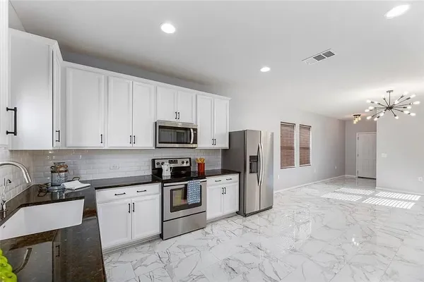 a large kitchen with a large refrigerator a stove top oven a sink dishwasher and cabinets