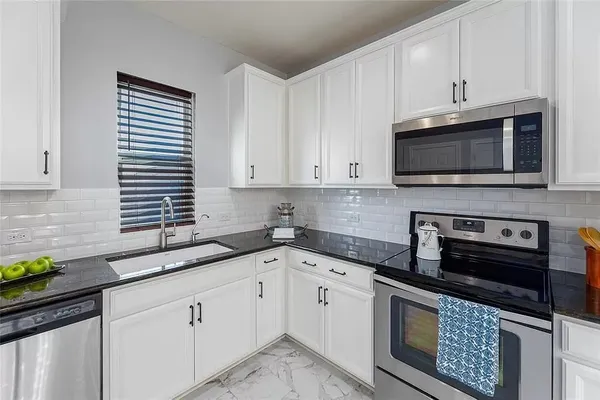 a kitchen with stainless steel appliances granite countertop a stove top oven a refrigerator a sink and dishwasher