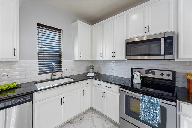 a kitchen with stainless steel appliances granite countertop a stove top oven a refrigerator a sink and dishwasher