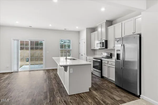 a kitchen with stainless steel appliances a sink a stove a refrigerator cabinets and wooden floor