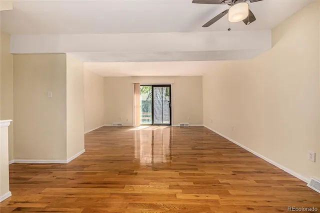 a view of an empty room with window and wooden floor