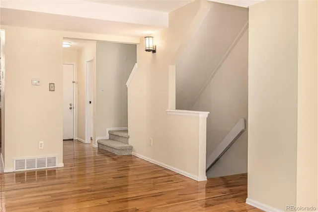 a view of a hallway with wooden floor and staircase