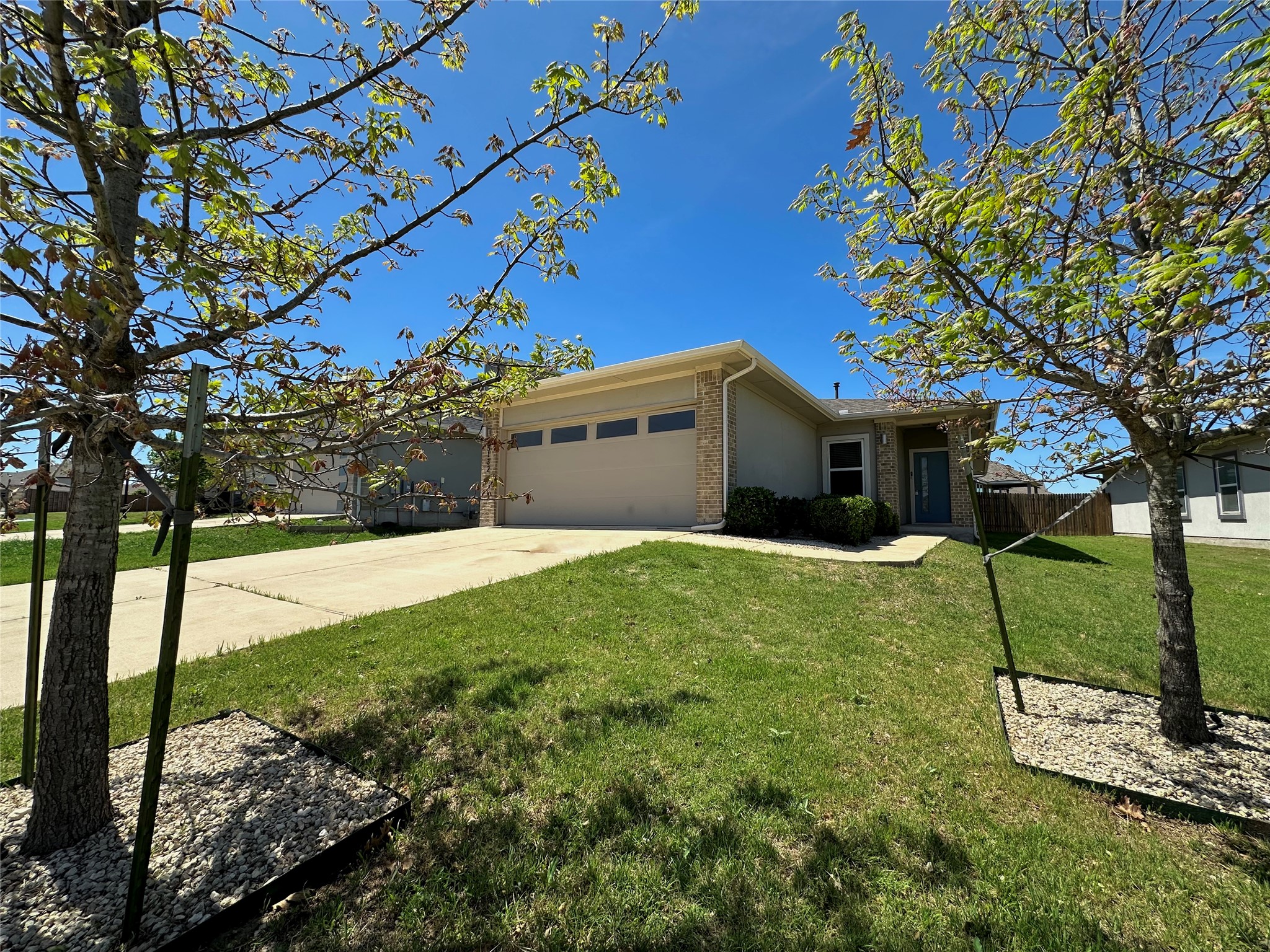 View of front facade with a garage, driveway, and brick siding