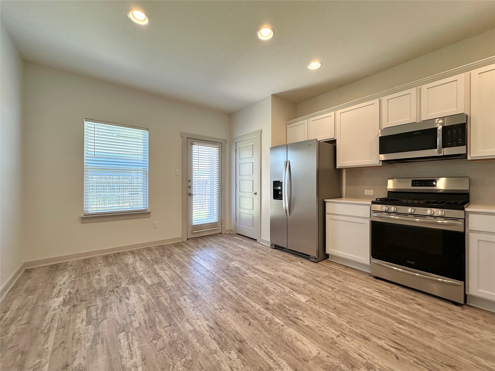 5132 Vanner Path Georgetown, TX 78626 - Photo 11 of 37 Kitchen featuring stainless steel appliances, light countertops, white cabinetry, light wood-style floors, and recessed lighting