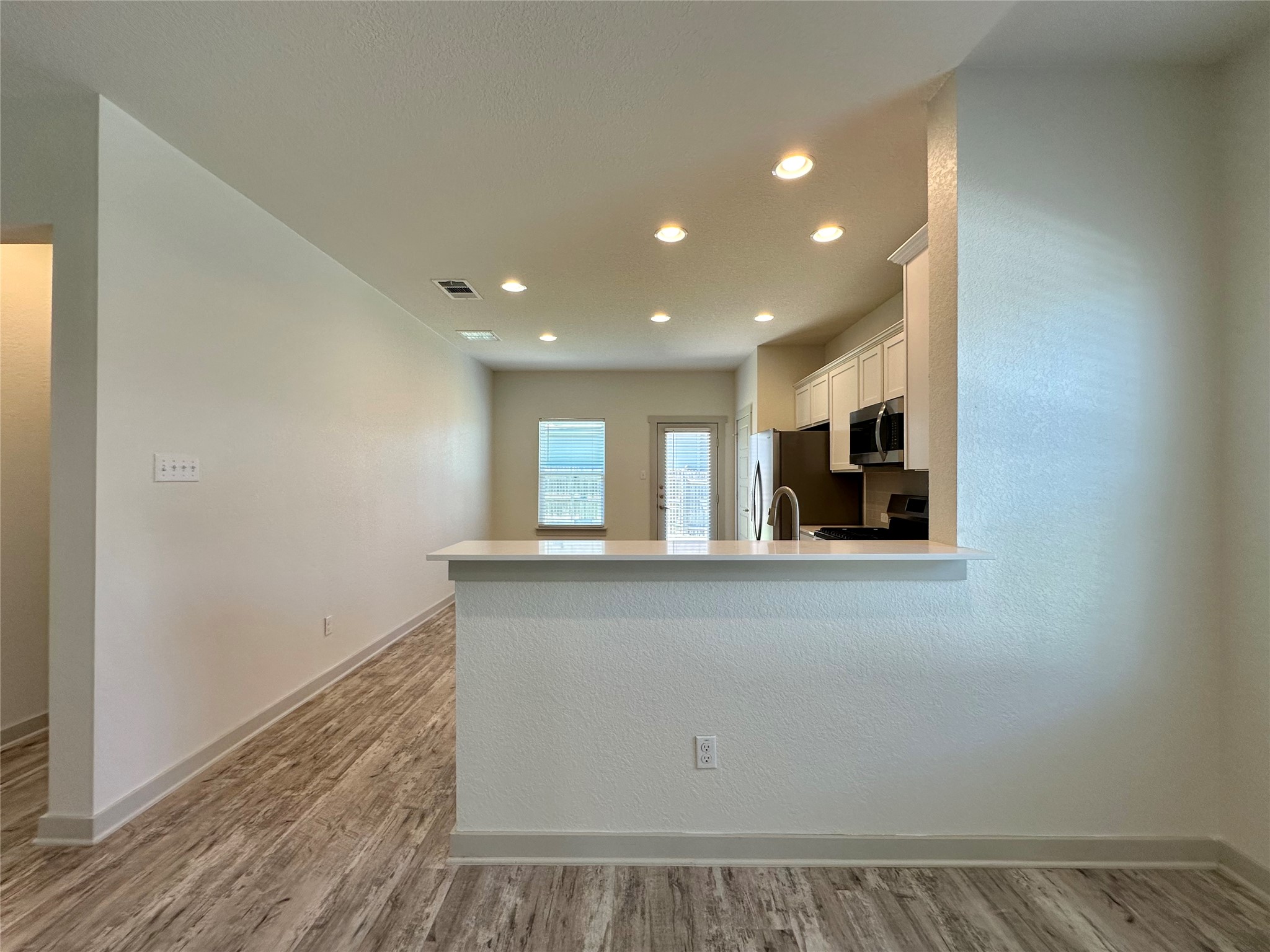 5132 Vanner Path Georgetown, TX 78626 - Photo 9 of 37 Kitchen featuring white cabinetry, a peninsula, light wood-style flooring, stove, and stainless steel microwave