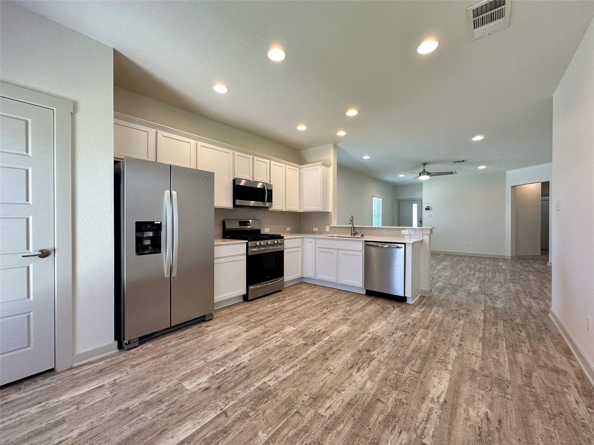 5132 Vanner Path Georgetown, TX 78626 - Photo 37 of 37 Kitchen featuring stainless steel appliances, white cabinets, light countertops, open floor plan, and recessed lighting