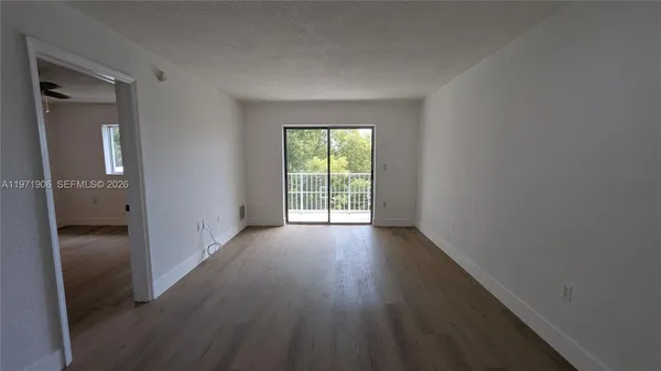 an empty room with wooden floor ceiling fan and windows