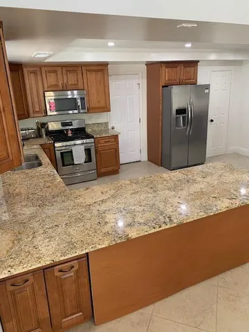 a kitchen with granite countertop a refrigerator and a stove top oven