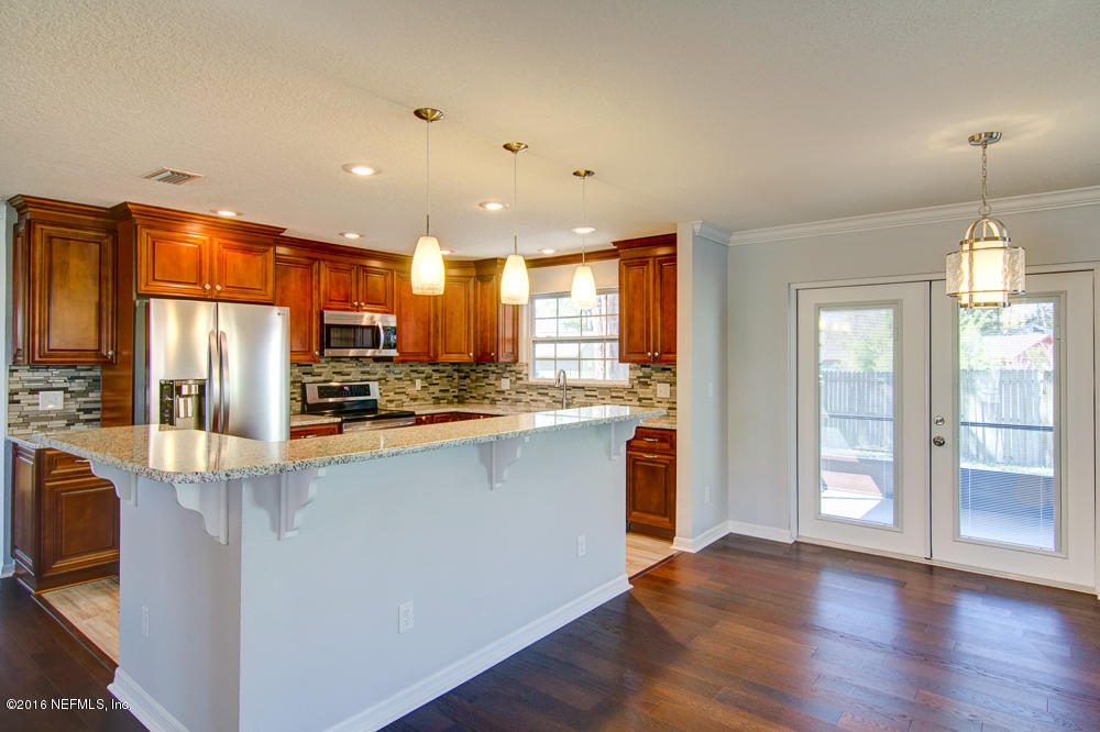 1634 Derringer Road Jacksonville, FL 32225 - Photo 9 of 41 a open kitchen with stainless steel appliances granite countertop a refrigerator a sink dishwasher a stove and a dining table with wooden floor