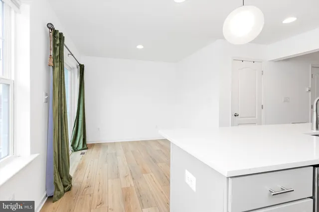 a large kitchen with kitchen island granite countertop a refrigerator a stove a sink and white cabinets with wooden floor