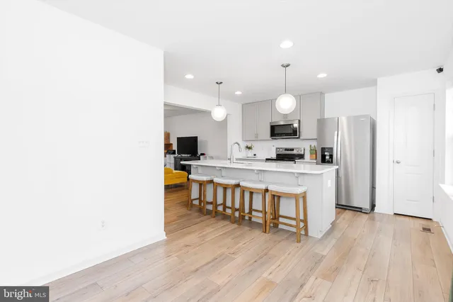 a kitchen with stainless steel appliances a stove top oven a sink a refrigerator and wooden floors