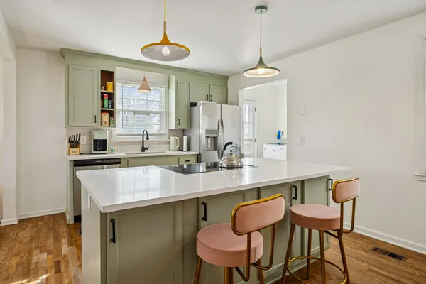 a kitchen with a dining table chairs a sink and dishwasher a refrigerator with wooden floor