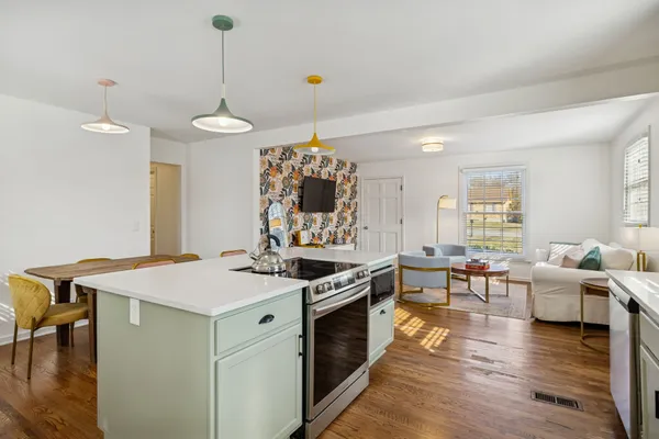 a open kitchen with stainless steel appliances granite countertop a stove and chairs with wooden floor