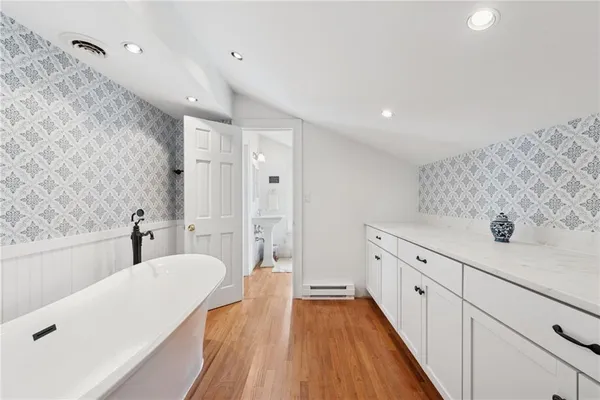a spacious bathroom with a tub sink and mirror