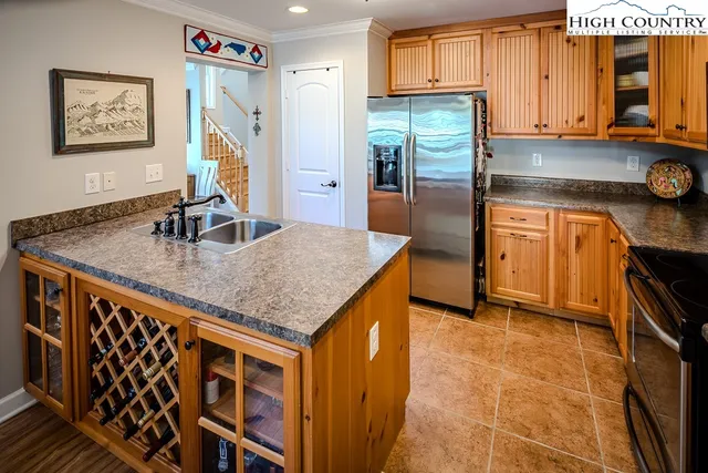 a kitchen with stainless steel appliances granite countertop a refrigerator a stove and a sink with wooden cabinets