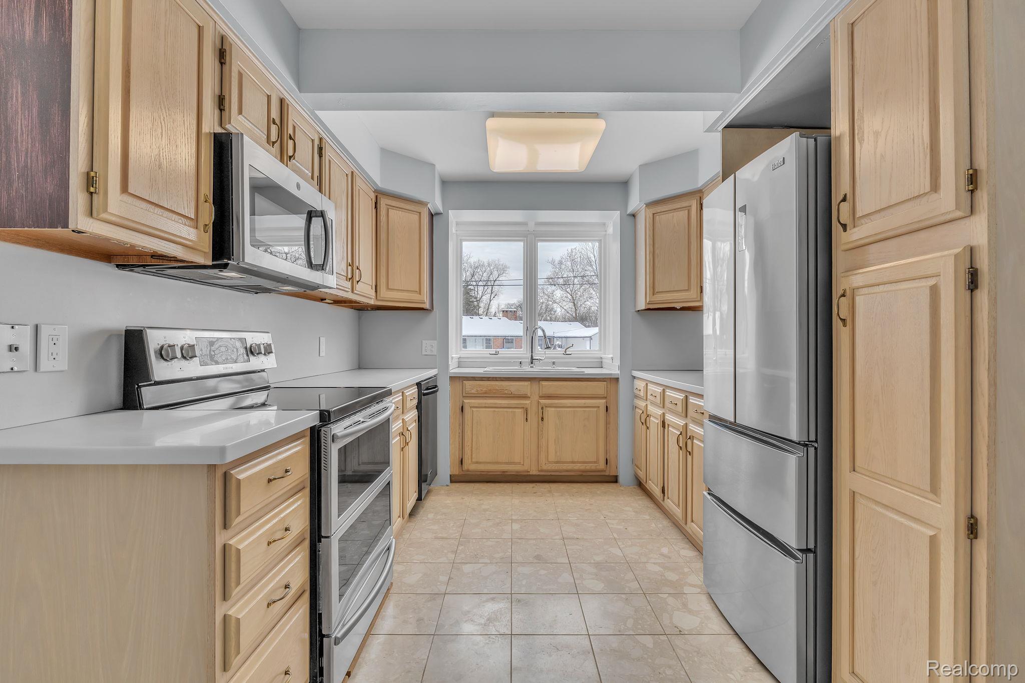 6576 Inkster Road West Bloomfield, MI 48322 - Photo 6 of 62 Kitchen featuring light brown cabinetry, range with two ovens, light countertops, freestanding refrigerator, and light tile patterned floors