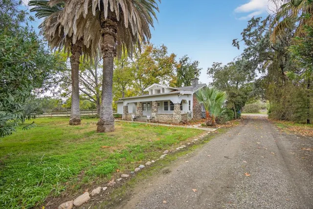 a front view of house with yard and trees in the background