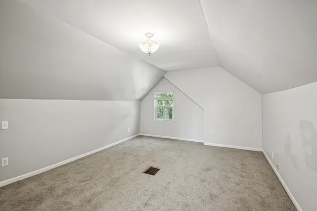 an empty room with a chandelier fan and windows