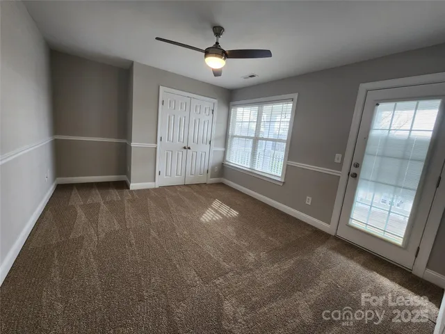 an empty room with ceiling fan and window