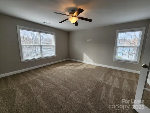 an empty room with windows and fan