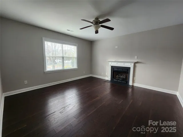 an empty room with wooden floor fireplace and windows