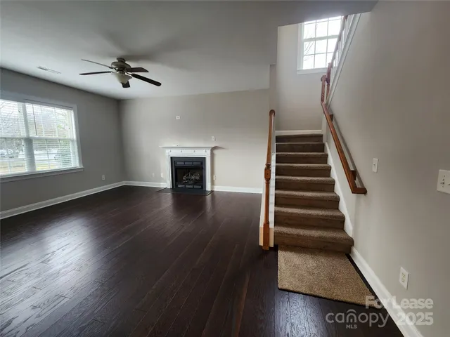 a view of an empty room with wooden floor fireplace and a window