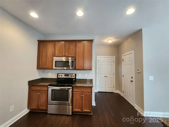 a kitchen with stainless steel appliances granite countertop a refrigerator a sink dishwasher a stove and white countertops with wooden floor