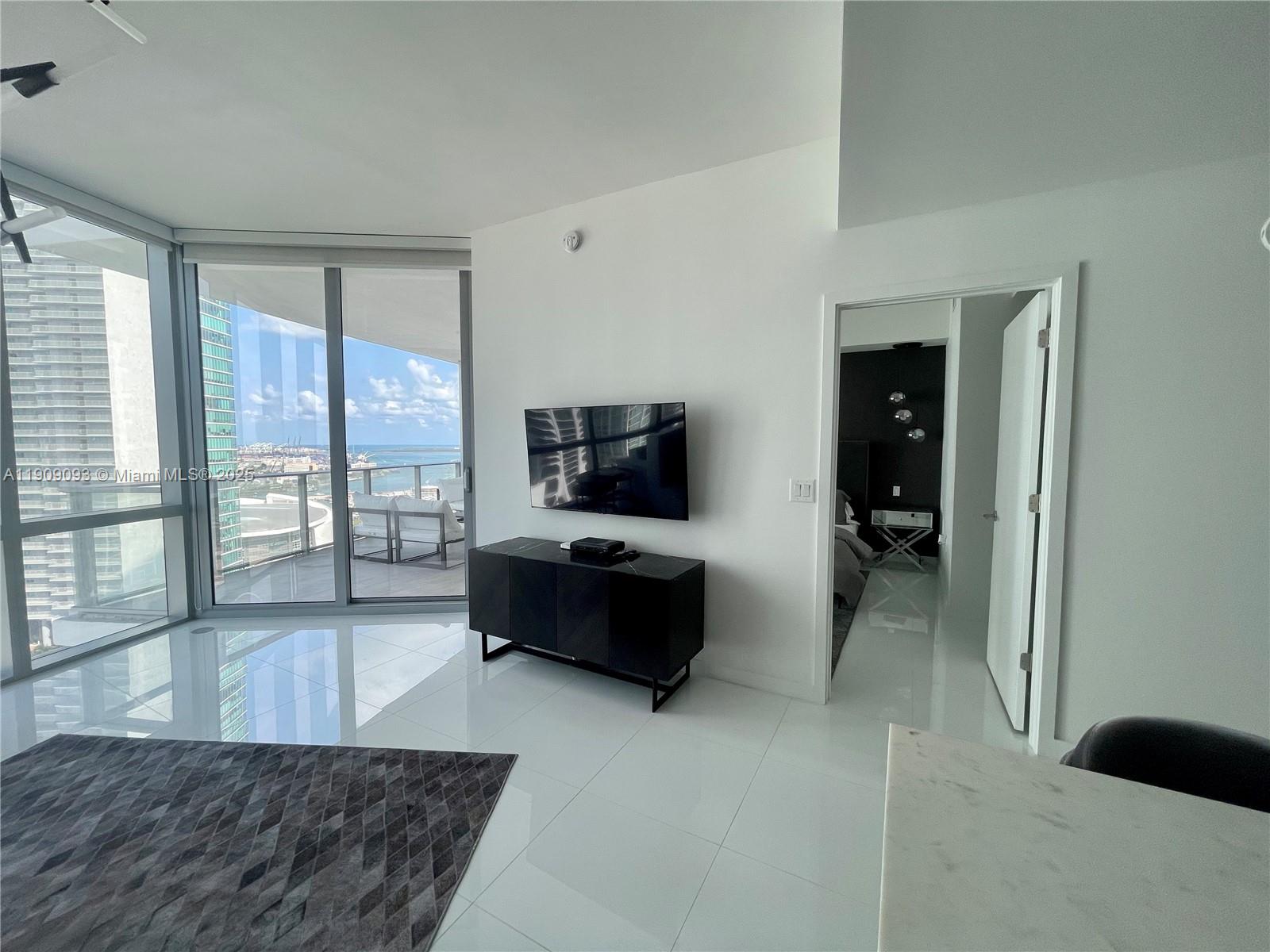 851 Northeast 1st Avenue, Unit 2403 Miami, FL 33132 - Photo 4 of 25 a living room with furniture and a flat screen tv