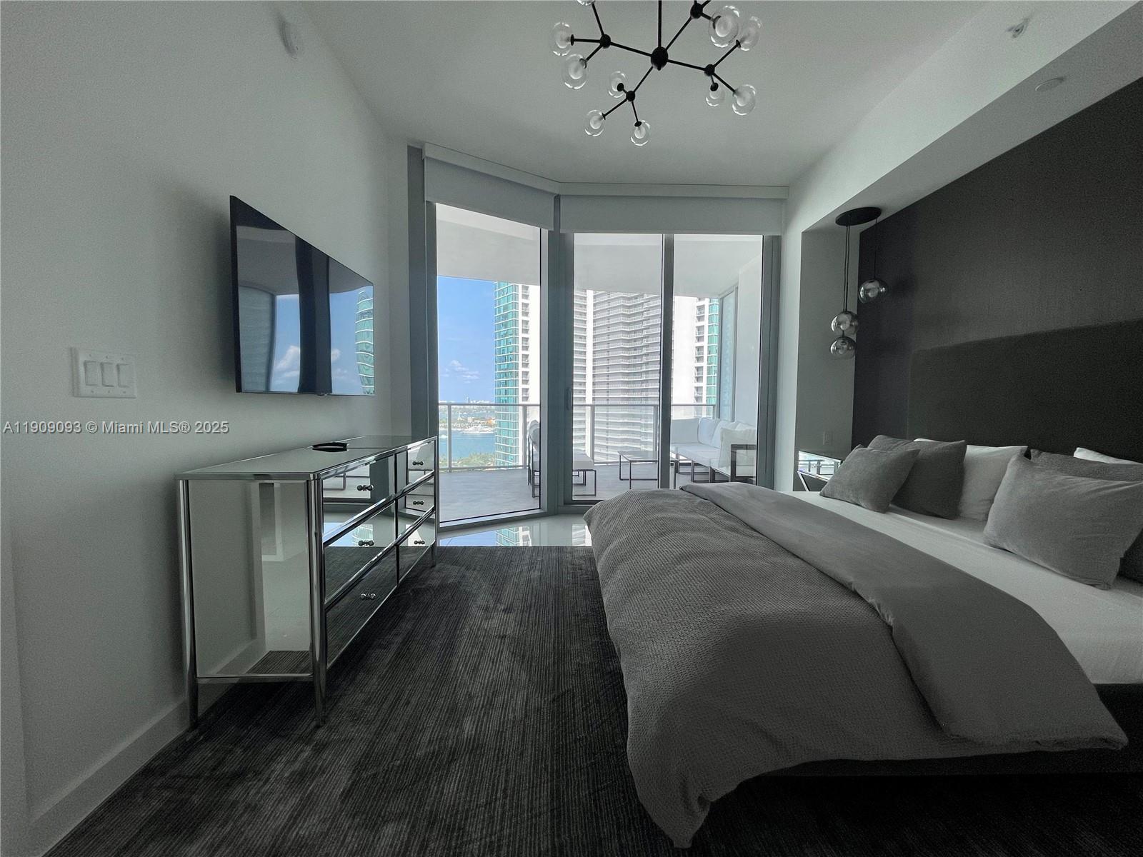 851 Northeast 1st Avenue, Unit 2403 Miami, FL 33132 - Photo 7 of 25 a spacious bedroom with a bed and a table in it