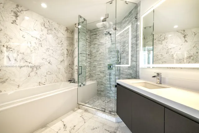 a bathroom with a bathtub sink vanity mirror and a shower
