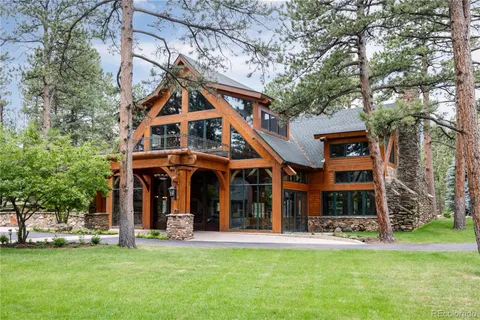 a view of a brick house with a big yard and large trees