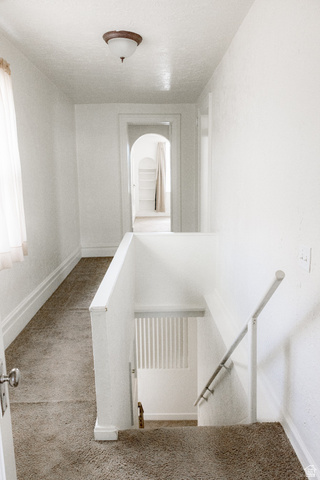 69 South Main Street Manti, UT 84642 - Photo 34 of 44 Carpeted hallway with a staircase, white painted walls, and a ceiling-mounted light fixture