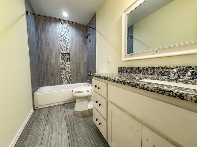 a bathroom with a granite countertop sink toilet and shower